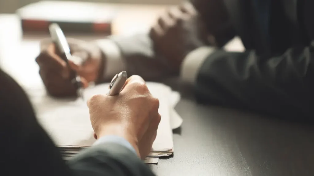 Two people at a desk with pens in hand